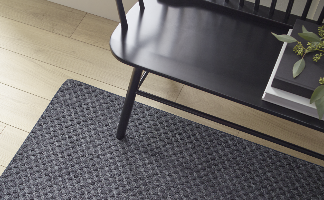 entryway with dark grey area rug over natural light hardwood floors